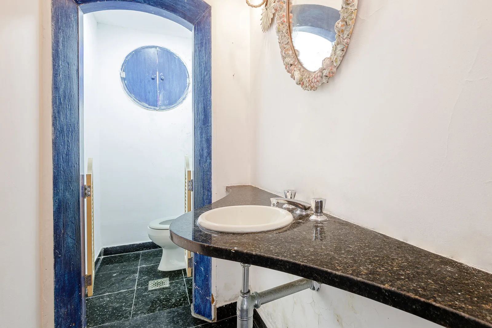 Une salle de bains avec une fenêtre ronde et un plan de marbre