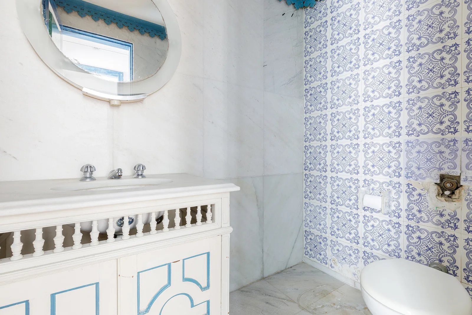 Une salle de bains en azulejos bleus avec un miroir rond