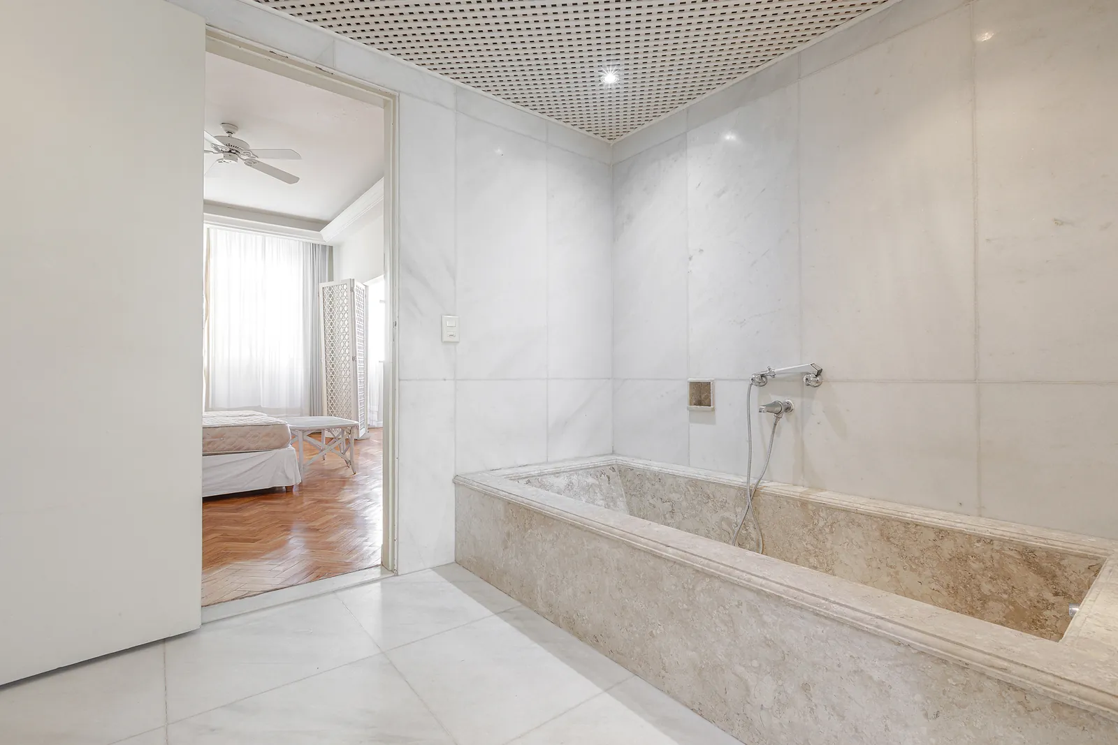 Une salle de bains en marbre avec baignoire encastrée