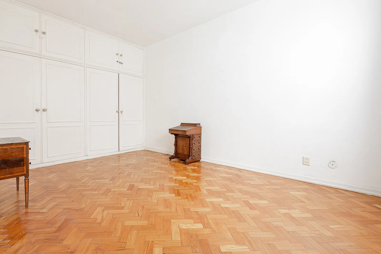 Une chambre avec penderie intégrée et parquet