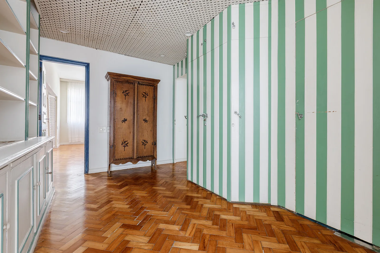 Une chambre au mur rayé de vert et une armoire en bois