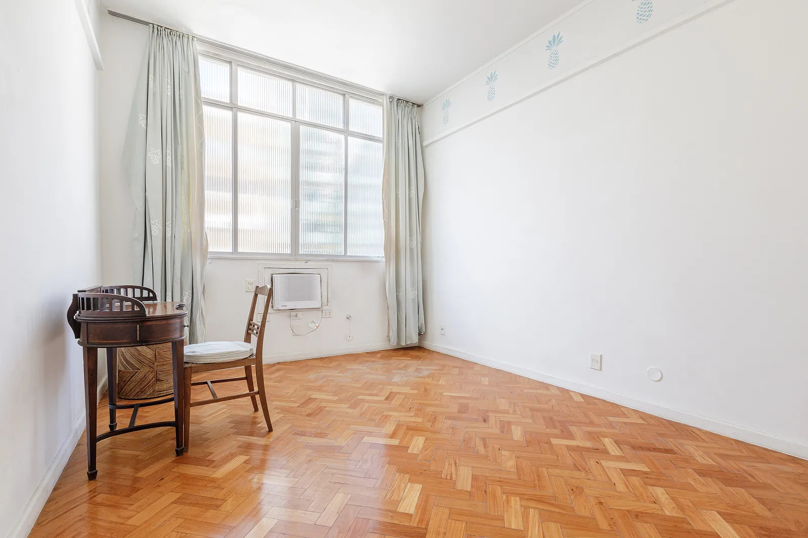 Une chambre avec une fenêtre et un parquet