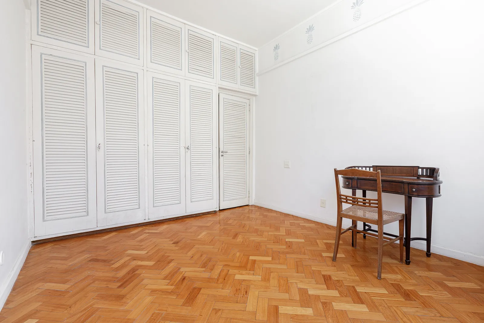 Une chambre aux placards blancs sculptés et parquet