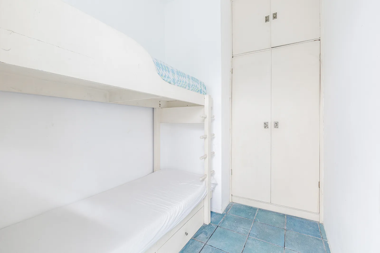 Une chambre simple en blanc avec rangements intégrés