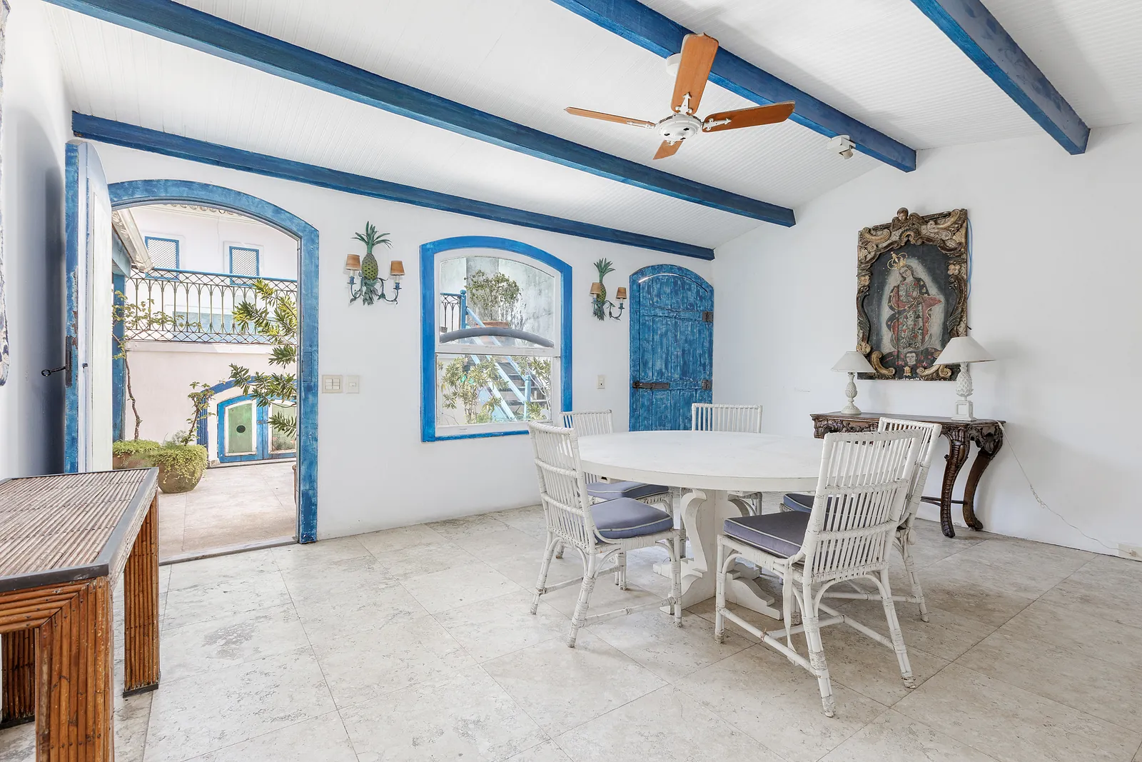 Un coin repas sous un ventilateur de plafond, arches d'azulejos à côté