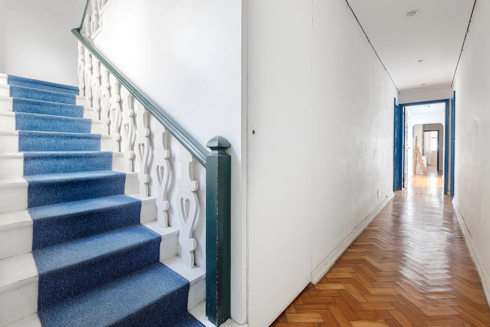 L'escalier du duplex, moquette bleue, et le couloir au fond