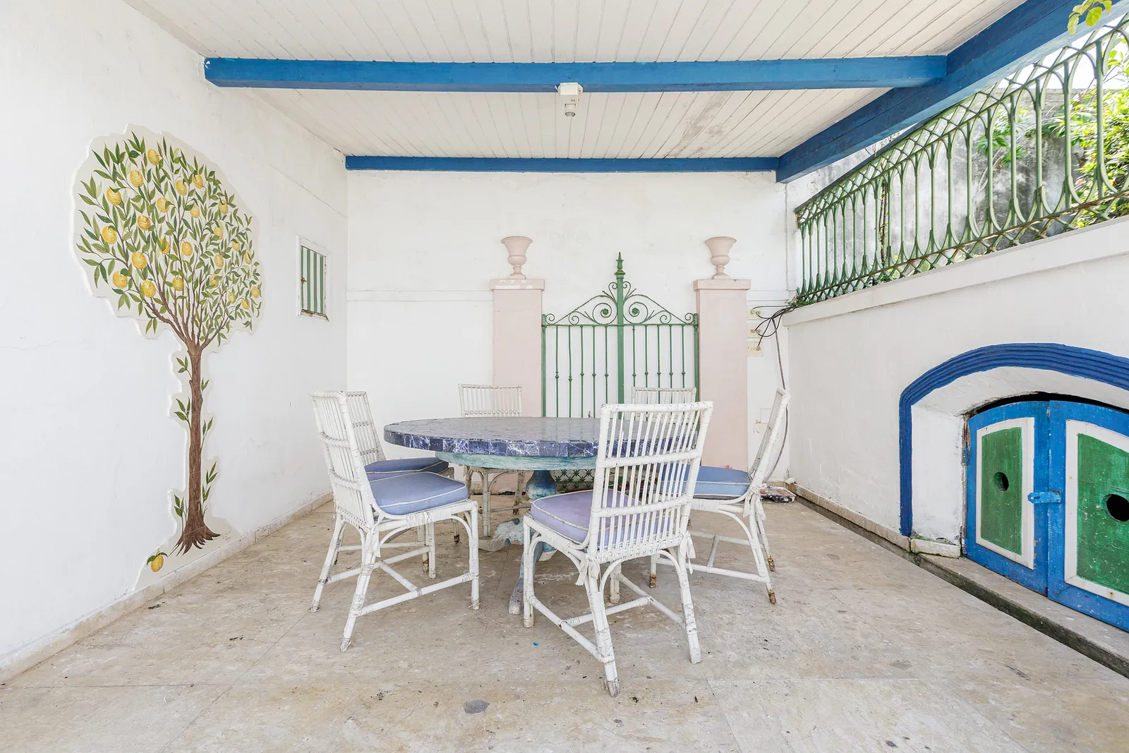 Une terrasse couverte dressée pour le repas, topiaire et chaises blanches