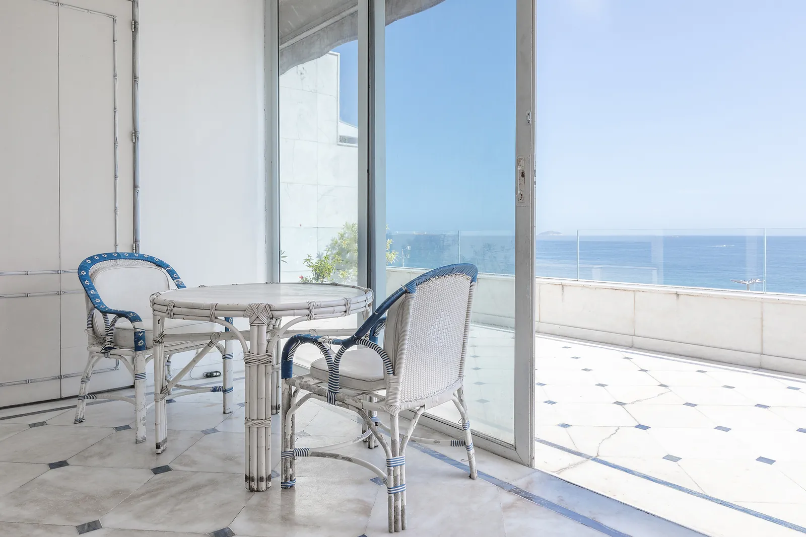 Un coin de terrasse avec une table, la mer à travers le verre